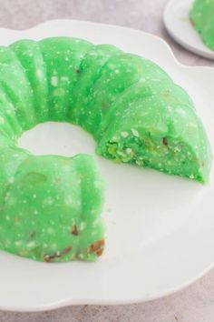 a green cake on a white plate with one slice cut out and ready to be eaten