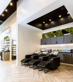 the interior of a salon with black chairs and wood flooring on the side wall