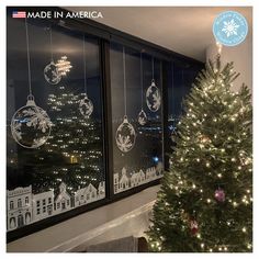 a christmas tree in front of two windows with ornaments hanging from the window sill