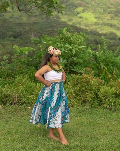 a woman standing in the grass with a flower crown on her head and wearing a skirt