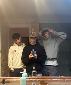 three young men standing in front of a bathroom mirror