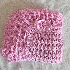 a pink crocheted purse sitting on top of a white blanket