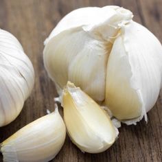 two heads of garlic sitting on top of a wooden table