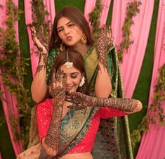 two women sitting on top of each other with their hands painted in hendi designs