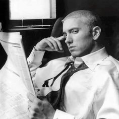 black and white photograph of man in dress shirt and tie looking at paper with hand on chin