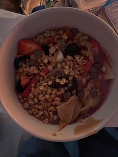 a white bowl filled with granola and fruit on top of a table next to a book