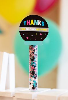 a thank you sign with confetti and sprinkles on it in front of balloons