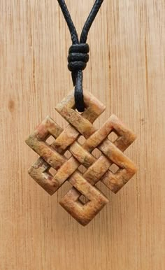 a small wooden object hanging from a string on a wood surface with a black cord