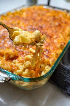 a spoon full of macaroni and cheese being lifted from a casserole dish