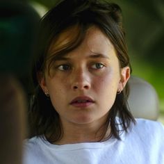 a close up of a person wearing a white shirt and looking at something in the distance