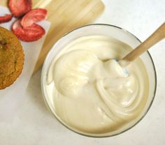 a cup of cream next to some cookies and strawberries