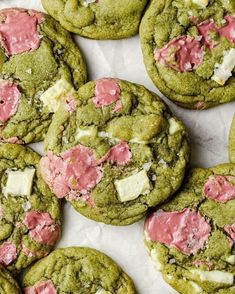 green cookies with pink and white frosting on top are shown in close up view