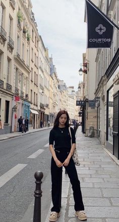 a woman standing on the side of a street next to tall buildings