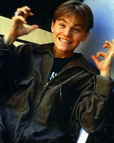 a young man sitting in a chair with his hand up to the side and smiling