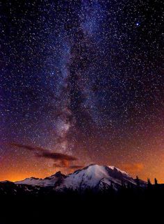 the night sky is filled with stars above mountains and snow - capped peaks in the distance