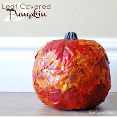 a painted pumpkin sitting on top of a table next to a white wall with the words leaf covered pumpkin written above it