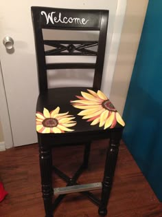 a black chair with sunflowers painted on it and the words welcome written in white