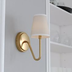 a wall light with a white shade on it in a room that has shelves and shelving