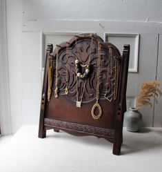 an old wooden clock with chains hanging from it's sides and a vase in the background