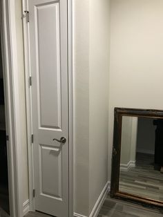 an empty room with a mirror and white door