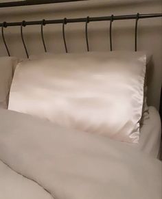 a bed with white sheets and pillows on it