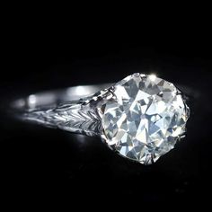 an old mine cut diamond engagement ring on a black background with the light shining through it