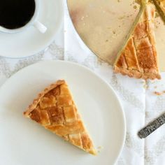 a piece of pie sitting on top of a white plate next to a cup of coffee