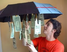 a man holding an umbrella with money hanging from it