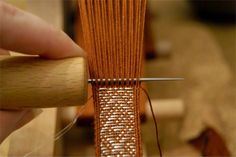 someone is working on an object that looks like a piece of wire and wood with two needles