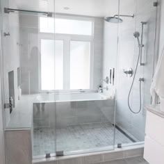 a bathroom with a walk in shower next to a bathtub and sink under a window