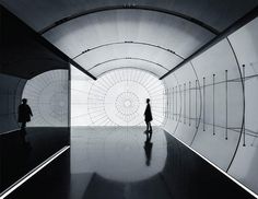 two people are walking through a tunnel in black and white photo with an abstract background