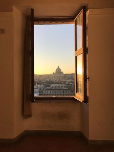 an open window with the view of a city in the distance and a building across from it