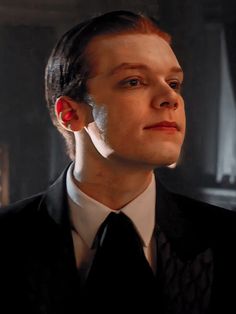 a man in a suit and tie with ear piercings looking off to the side