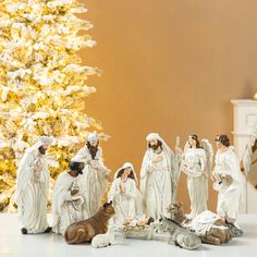 a group of figurines sitting next to a christmas tree