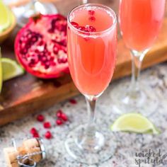 two wine glasses filled with pomegranate and garnish on a cutting board