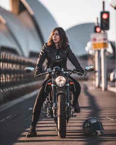 a woman sitting on top of a motorcycle next to a traffic light