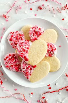 valentine's day cookies on a plate with pink and red sprinkles