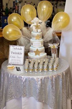 a table topped with a cake covered in gold and white balloons next to a sign that says twinkle