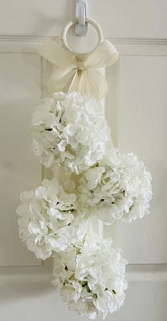 a bunch of white flowers hanging from a hook on a door with a ribbon around it