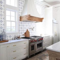 a kitchen with an oven, stove and counter top in the center is decorated with geometric wallpaper