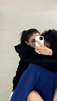 two women hugging each other while taking a selfie with their cell phone in front of them