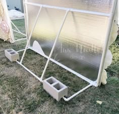 a white metal structure sitting on top of a grass covered field