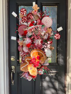 a christmas wreath on the front door with candy canes, candies and gingerbreads