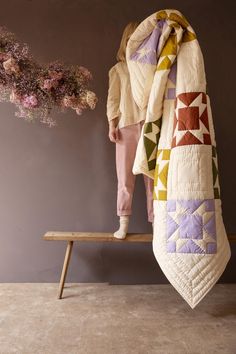 a woman is standing on a bench with a quilt draped over her head and holding a flower