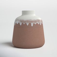 a brown and white vase sitting on top of a table