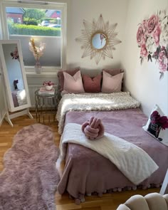 a bed room with a neatly made bed next to a mirror and flowers on the wall