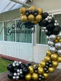 a graduation balloon arch with black, gold and silver balloons