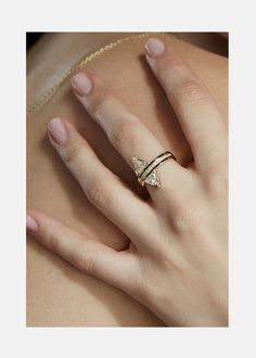 a woman's hand wearing a gold ring with two diamonds on the middle finger