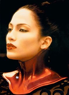 a woman with her head turned to the side wearing red leather collared top and earrings