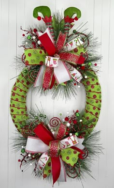 a christmas wreath hanging on the side of a white door with green and red decorations